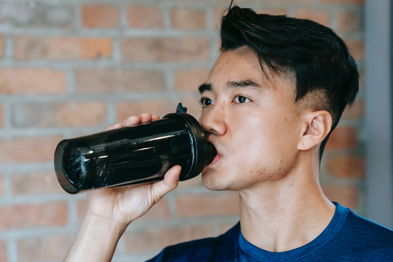 man in gym drinking vegan protein powder