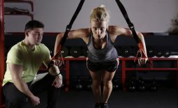 woman exercising with personal trainer in gym