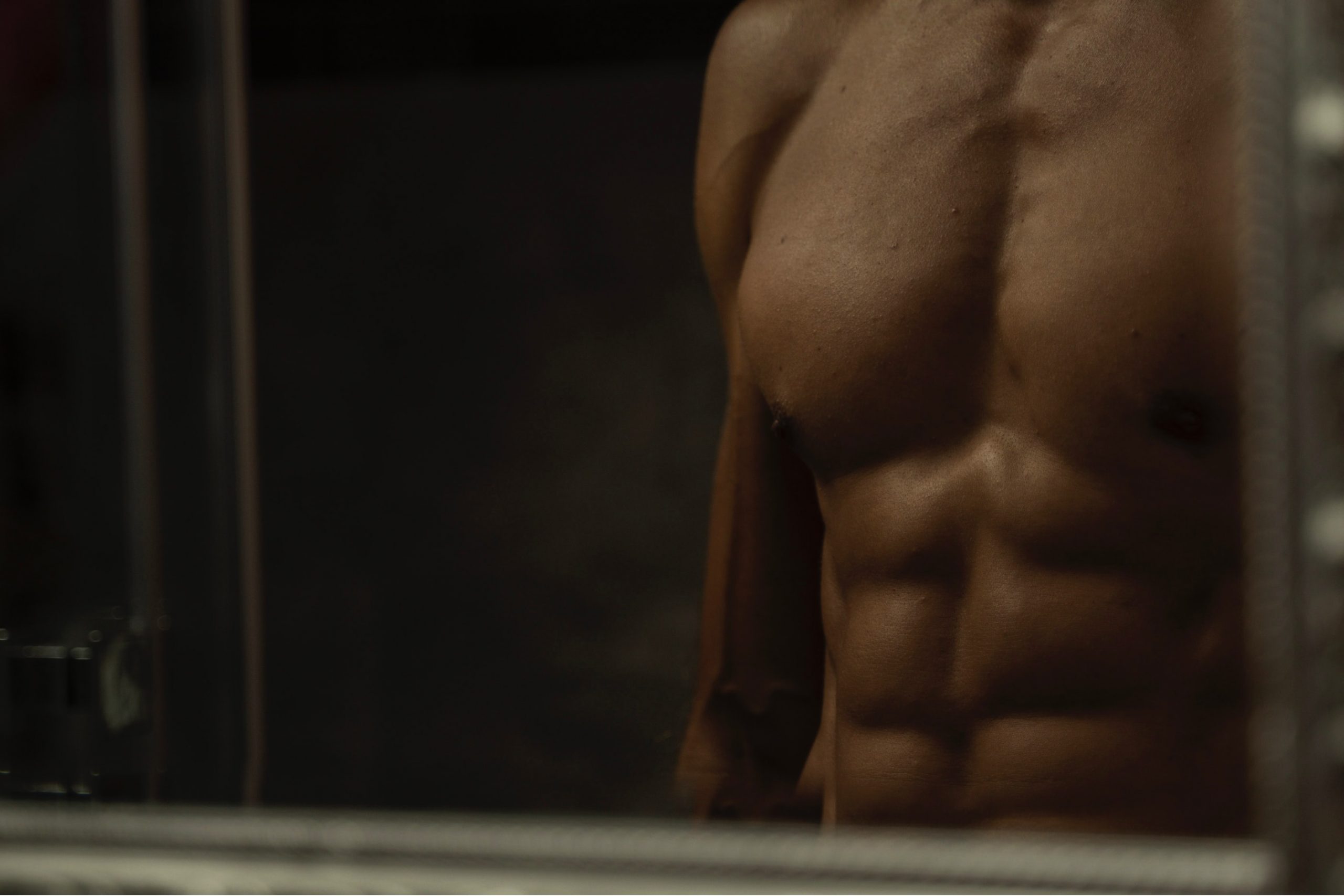 Man with shredded abs in front of a mirror